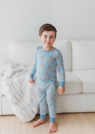 Child wearing blue pajamas with bunny pattern on a white couch.