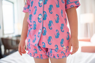 Child wearing pink pajamas with blue seahorse patterns in a bedroom setting.