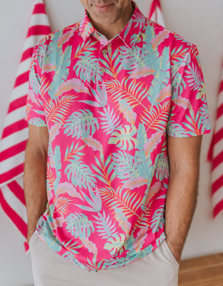 Person wearing a vibrant pink tropical shirt with colorful patterns, standing against a neutral background.