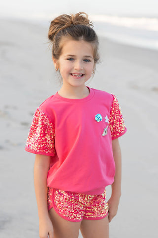 pink sequin outfit with sparkle shells on a beach