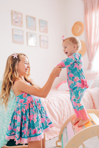 Two children in matching floral outfits standing in a bedroom.