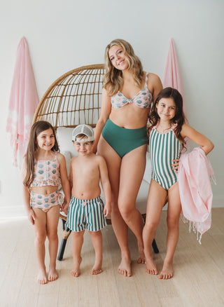 Family in matching swimsuits posing together in a stylish indoor setting.