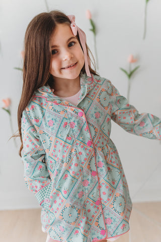Young girl wearing a patterned rain jacket with a white background