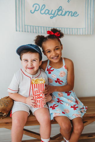 Two children sitting on a bench with popcorn, smiling at the camera.