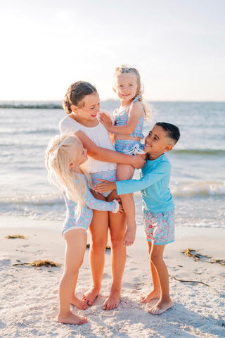 Four children playing on a sandy beach with ocean in the background