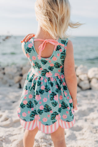 Child wearing a floral dress on a beach