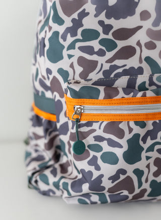 Camouflage-patterned backpack with orange zipper on a light gray background