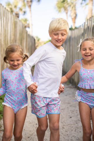 Three children in matching outfits walking together outdoors.