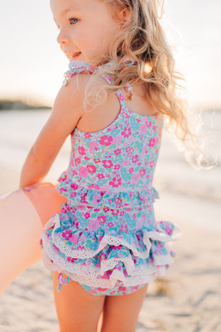 Child wearing a floral swimsuit on a beach