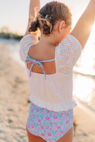 Child in a floral swimsuit on a beach