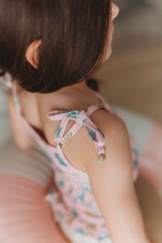 Close-up of a child's back with a pink dress and decorative straps.