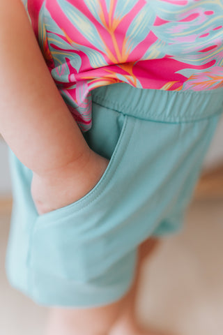 Person wearing a colorful top and light blue shorts with a blurred background