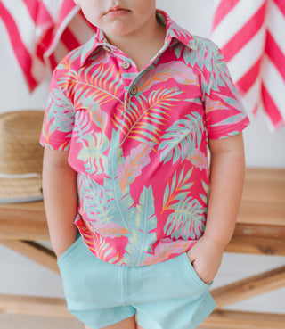 Child wearing a colorful tropical shirt with a pink background