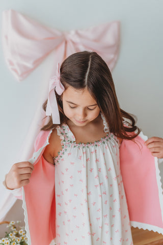 Young girl wearing pink cardigan over romper