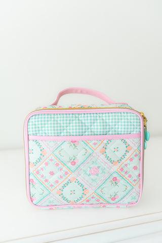 Patchwork-patterned lunch bag with pink accents on a white background
