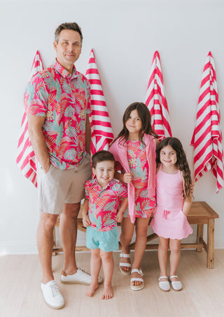 Family of five posing together with red and white striped towels in the background.
