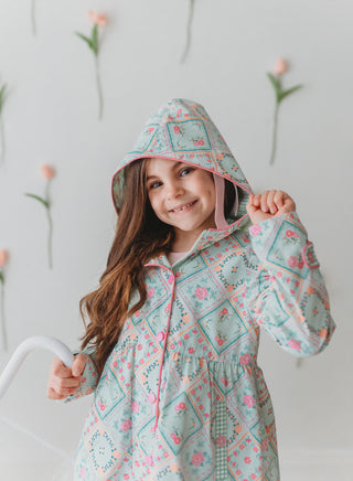 Young girl wearing a floral patterned raincoat against a light background